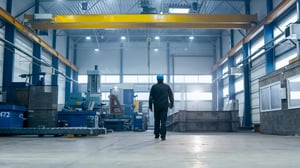 Factory worker in a hard hat is walking through industrial facilities
