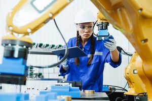 operator inspecting CNC machine tending robot